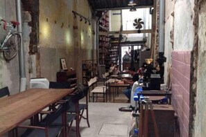Un espacio reducido con una mesa y sillas de madera, una bicicleta y un ventilador.