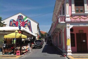 A narrow street with buildings on either side, some with balconies and a few with ground-level shops. - Phuket Town Budget House - Aircon Room #1 (Phuket)