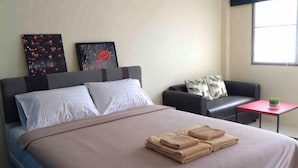 A hotel room with a bed, a sofa, a small table with a plant, and artwork on the wall. - Phuket Town Budget House - Aircon Room #1 (Phuket)