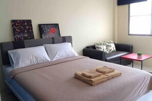 A hotel room with a bed, a sofa, a small table with a plant, and artwork on the wall. - Phuket Town Budget House - Aircon Room #1 (Phuket)