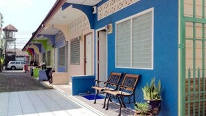 A building with a blue exterior, a gated entrance, and a tiled walkway. - Phuket Town Budget House - Aircon Room #1 (Phuket)