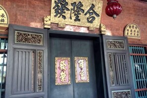 A traditional building with a large wooden door, decorative panels, and a sign above the door. - Phuket Town Budget House - Aircon Room #1 (Phuket)
