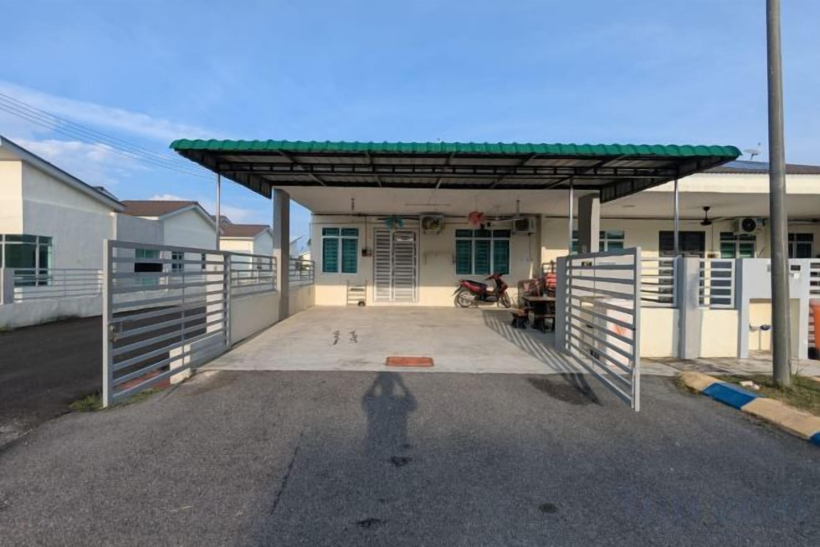 A covered parking area with a gated entrance, a motorcycle, and a building with a green roof.