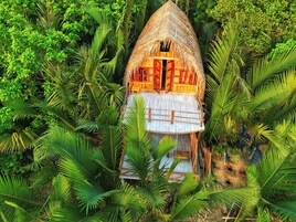 Uma cabana com telhado de palha cercada por vegetação tropical exuberante.