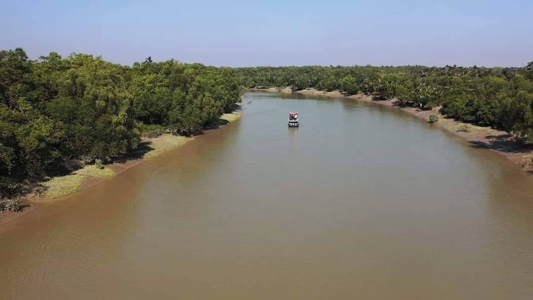 Un río con densa vegetación a ambos lados y una embarcación en el centro.