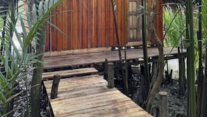 A wooden structure with a thatched roof, surrounded by lush greenery. - Iraboti Eco Resort & Research Center (Dacope)