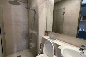 A bathroom with a glass shower enclosure, a sink, and a mirror. - Park Point Inn @ Cengkareng (West Jakarta)