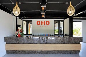 A reception desk with a sign reading 'OHO PHUKET' and a plant on the left. - Oho Luxury Pool Access (Phuket)