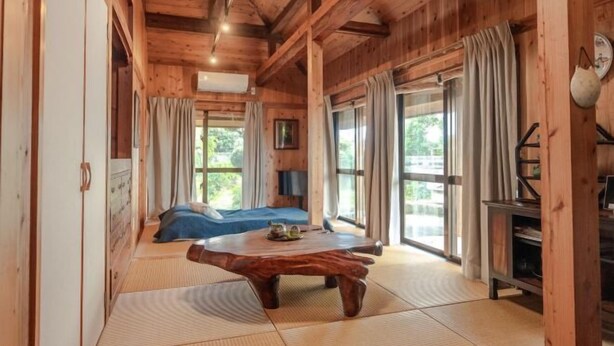 Ein Holzinterieur mit einem Bett, einem Holztisch und einem großen Fenster.