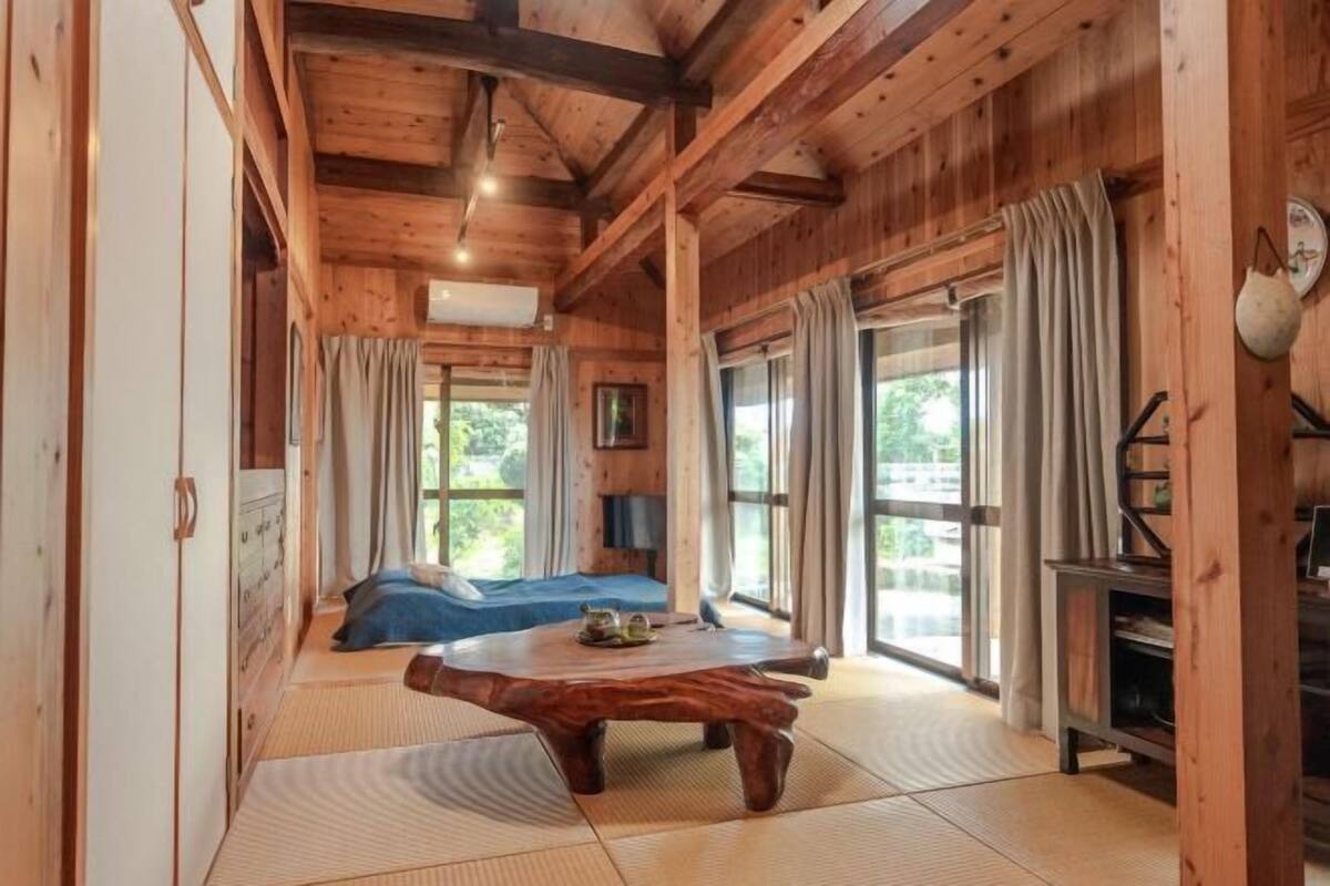 Un intérieur en bois comprenant un lit, une table basse en bois et une grande fenêtre.