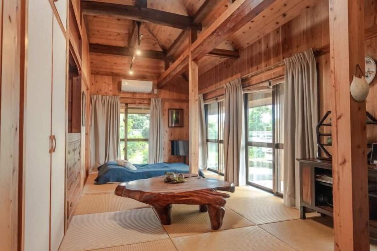 Un intérieur en bois comprenant un lit, une table basse en bois et une grande fenêtre.