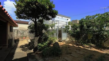 Um imóvel residencial com jardim, estufa e céu claro.