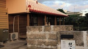 Ein traditionelles japanisches Gebäude mit einem Ziegeldach und einer Steinwand davor.
