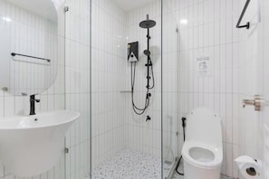 A bathroom with a white sink, a toilet, and a shower area.