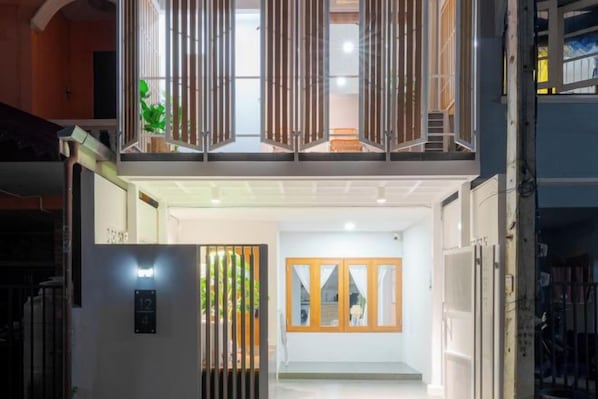 A hotel entrance with a modern design, featuring a glass door, a staircase, and a view of the interior.