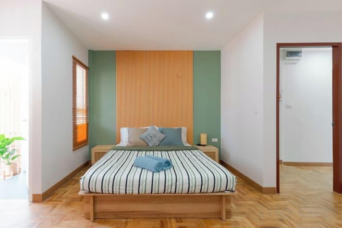 A bedroom with a bed, a wooden headboard, a bedside table, and a nightstand.