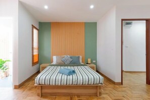 A bedroom with a bed, a wooden headboard, a bedside table, and a nightstand. - Modern Townhome / 2BR near CNX moat (Chiang Mai)