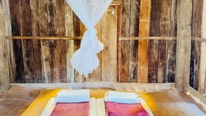 Une chambre rustique aux murs en bois, avec un lit recouvert d’une couvre-lit à motifs et un lit à baldaquin.
