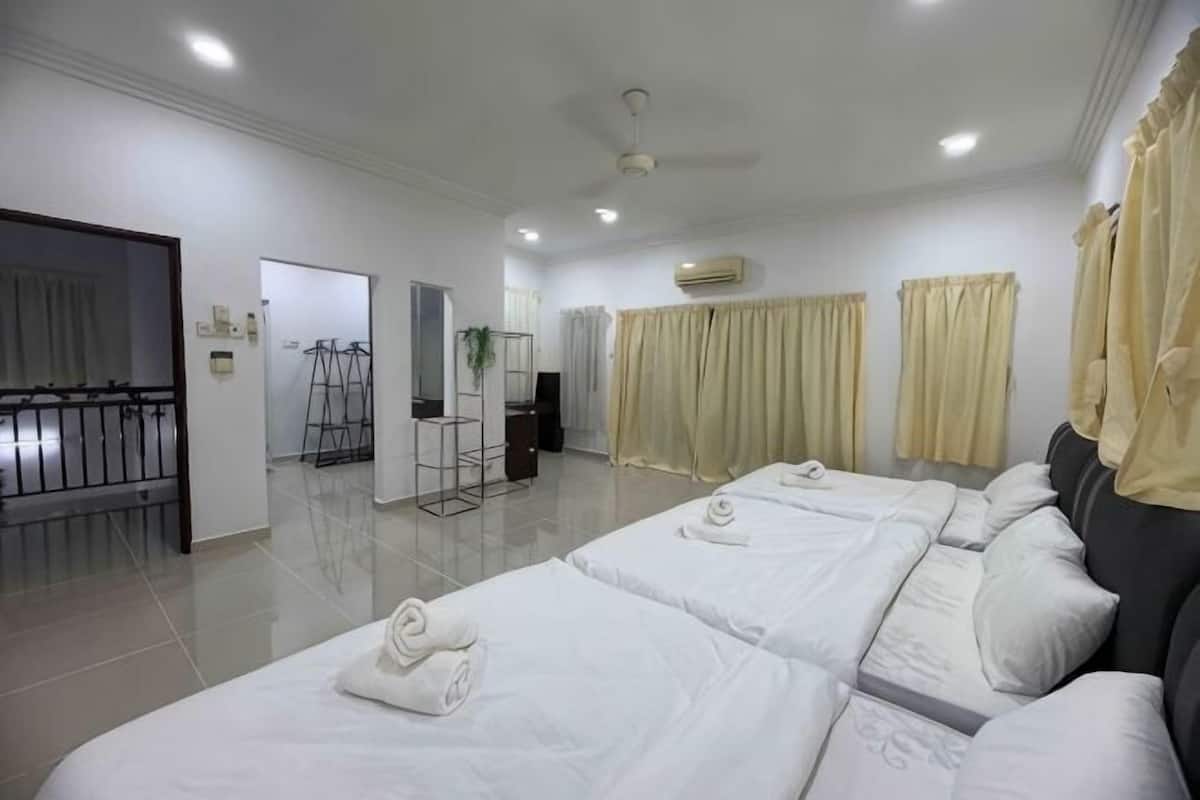 Habitación de hotel con dos camas, un balcón, un espejo, una planta y una ventana con cortinas.