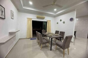 Un área de comedor con una mesa, sillas, un ventilador de techo y una puerta que da a otra habitación.