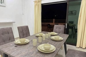 A dining table set with plates, bowls, and cups, surrounded by chairs.
