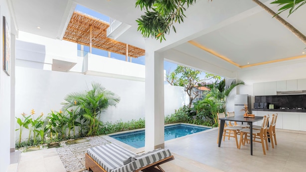 A modern outdoor living area with a pool, lounge chairs, and a dining set. - Moon Light Villa (Munggu)