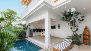 A modern outdoor living area with a pool, a wooden deck, and a lounge chair. - Moon Light Villa (Munggu)