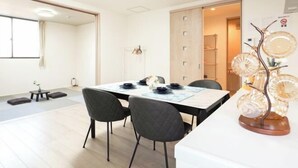 A modern dining area with a table set for four, black chairs, and a decorative glass sculpture. - youmeiyado asahi matu 3F (Osaka)
