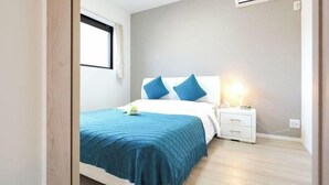 A bedroom with a bed, bedside table, and an air conditioning unit. - youmeiyado asahi matu 3F (Osaka)