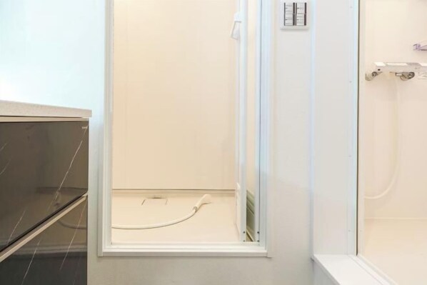 Un baño con cabina de ducha de vidrio, un lavabo blanco y un espejo.