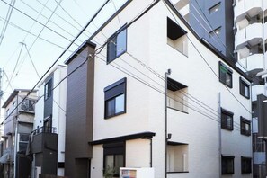 A multi-story residential building with a flat facade, multiple windows, and visible electrical wiring. - youmeiyado asahi matu 3F (Osaka)