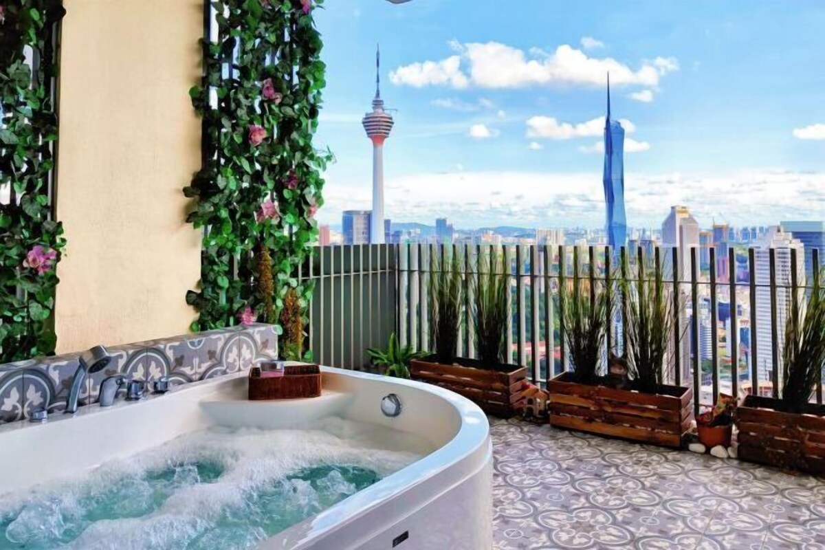 Un bain à remous avec vue sur le paysage urbain, entouré de verdure et doté d’un sol à motifs.