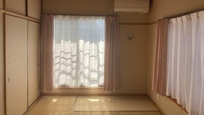 A room with tatami flooring, sliding doors, and an air conditioning unit. - Flower Tea Hotel (Tokyo)