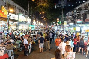 A crowded street with people walking and sitting, indicating a busy urban area. - Berjaya Times Square 1BR Suite 5Pax Bukit Bintang Steps to Monorail (Kuala Lumpur)