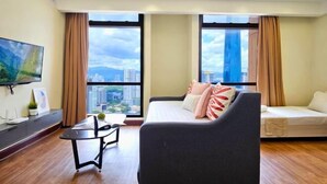 A modern living room with a sofa, a small table, and a TV mounted on the wall. - Berjaya Times Square 1BR Suite 5Pax Bukit Bintang Steps to Monorail (Kuala Lumpur)