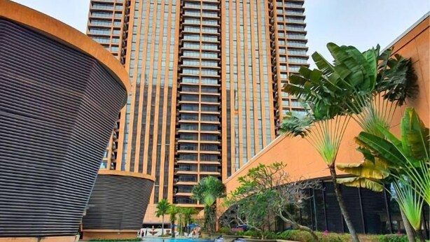 A modern hotel with a swimming pool, surrounded by lush greenery and tall buildings. - Berjaya Times Square 1BR Suite 5Pax Bukit Bintang Steps to Monorail (Kuala Lumpur)