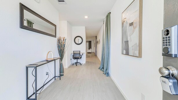 A hallway with a desk, chair, and a wall-mounted security device.