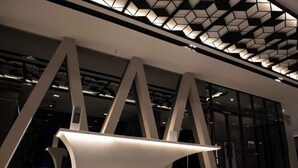 A modern interior with geometric ceiling design, a central illuminated structure, and large windows. - Expressionz#KLCC#1BR#Skypool#NEW (Kuala Lumpur)
