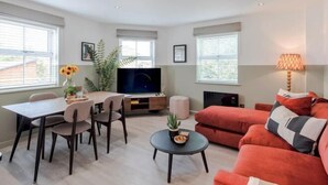Een moderne woonkamer met een eethoek, een televisie en een bank.