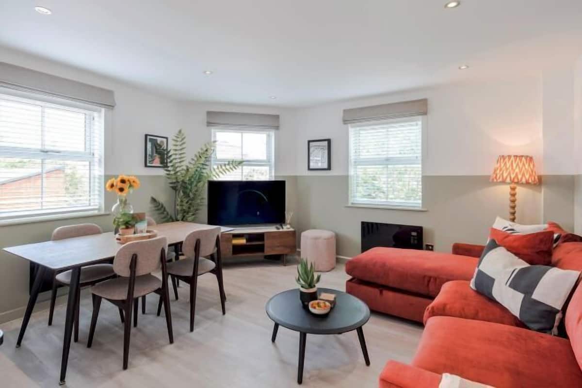 Een moderne woonkamer met een eethoek, een televisie en een bank.