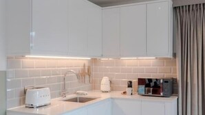 Een moderne keuken met witte kasten, een inbouwspoelbak, een broodrooster, een waterkoker en een magnetron.