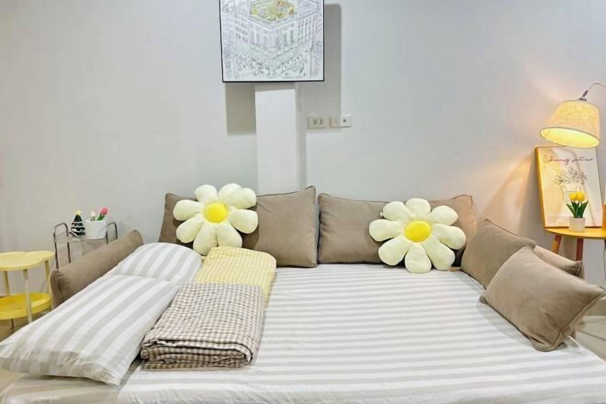 A hotel room with a bed, pillows, a lamp, a small table, and a wall art piece.