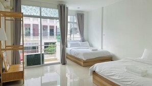 Ein Hotelzimmer mit großem Fenster, hölzernem Bettgestell, Nachttisch und Blick ins Freie.