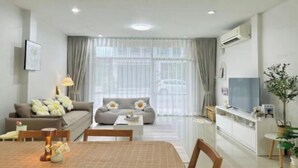 Ein modernes Wohnzimmer mit Sofa, Esstisch und Fernseher.