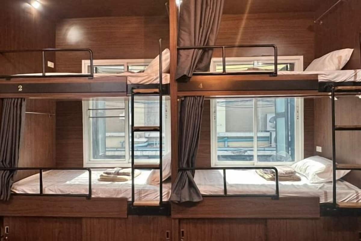 A bunk bed room with wooden walls, a window, and curtains.