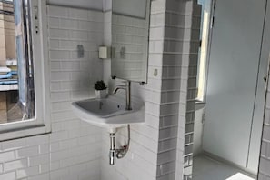 A bathroom with a white sink, a mirror, and a window. - Seen Hostel Bangkok The Riverwalk (Bangkok)