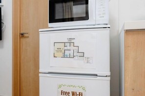A kitchen with a microwave and a refrigerator. - Senju Kotobukicho 1F (Tokyo)