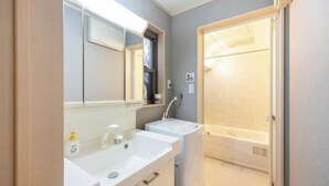 A bathroom with a white sink, mirror, and shower. - CROWN OOJIMA (Tokyo)