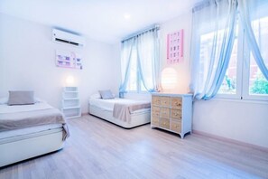 Un dormitorio con cama, cómoda, ventana con cortinas y unidad de aire acondicionado.