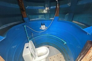 Una bañera azul con inodoro en su interior, rodeada de paredes de madera.